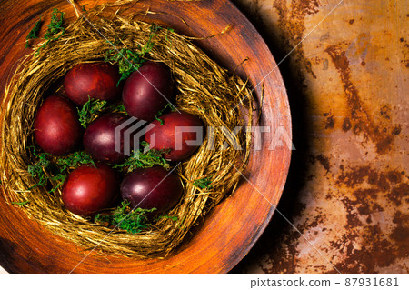 Beautiful red Easter eggs in a nest of straw on a plate 87931681