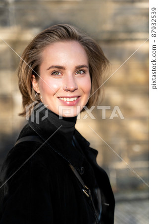 Young blond smiling short-haired woman in velvet coat and sweater on sunny day 87932539