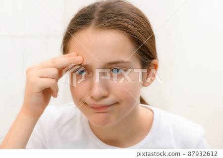 face of teenage girl, she looks at herself in the mirror and touches her face with her hand, she is upset and has frustrated emotions face of teenage girl, she looks at herself in the mirror and touches her face with her hand, she is upset and has frustrated emotions 87932612