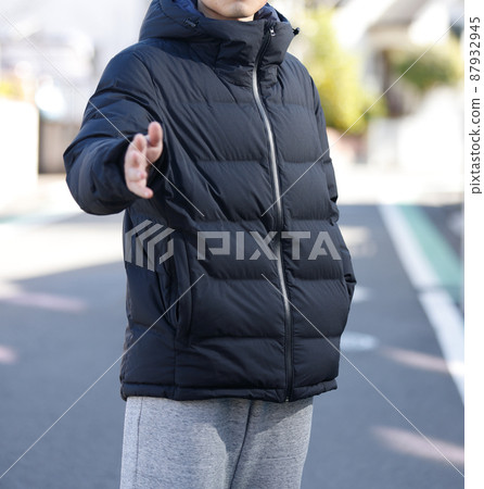 A man in a down jacket standing in the city 87932945