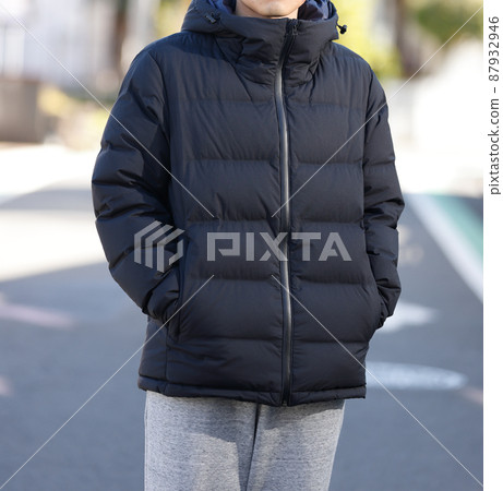 A man in a down jacket standing in the city 87932946