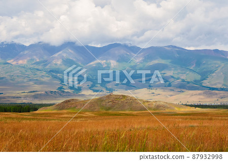 Viewing platform in the Kurai steppe in Altai. Dramatic rainy alpine landscape in green valley and mountain sharps in low clouds. Atmospheric awesome view to pointy mountain in low clouds. 87932998