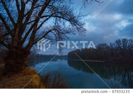 a beautiful autumn landscape in the evening - forest with river and cloudy sky a beautiful autumn landscape in the evening - forest with river and cloudy sky 87933235