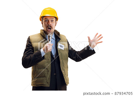 Portrait of young man in helmet, professional commentator, journalist with microphone broadcasting isolated over white background. News, emotions, job concept 87934705