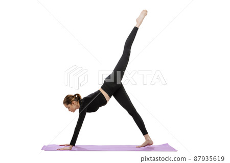 Portrait of young sportive girl doing exercises on purple sport mat isolated over white studio background 87935619