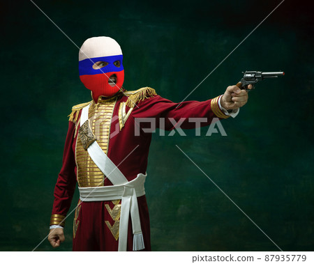 Portrait of man in suit as Nicholas II wearing red, white and blue balaclava isolated on dark green background. Retro style, comparison of eras concept. History Portrait of man in suit as Nicholas II wearing red, white and blue balaclava isolated on dark green background. Retro style, comparison of eras concept. History 87935779