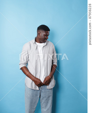 An African-American man in white clothes stands on an isolated blue background 87938228