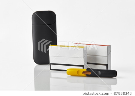Black and yellow electronic cigarette, battery, two packs and one of them with red side, isolated on white. Heating tobacco system. Close up Black and yellow electronic cigarette, battery, two packs and one of them with red side, isolated on white. Heating tobacco system. Close up 87938343
