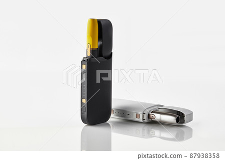 New generation black and yellow, white electronic cigarettes in open batteries isolated on white. Heating tobacco system. Advertising, close up New generation black and yellow, white electronic cigarettes in open batteries isolated on white. Heating tobacco system. Advertising, close up 87938358
