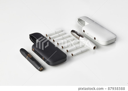 New generation black and white, two electronic cigarettes and two open batteries, seven heatsticks isolated on white. Heating tobacco system. Close up New generation black and white, two electronic cigarettes and two open batteries, seven heatsticks isolated on white. Heating tobacco system. Close up 87938388