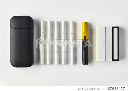 New generation black and yellow electronic cigarette and battery, one pack and ten heatsticks isolated on white. Heating tobacco system. Close up New generation black and yellow electronic cigarette and battery, one pack and ten heatsticks isolated on white. Heating tobacco system. Close up 87938457