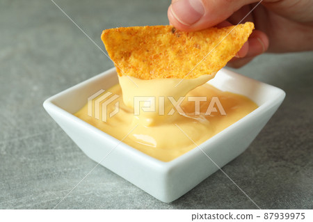 Female hand dips chip in cheese sauce, close up 87939975