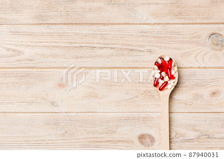 Vitamin capsules in a wooden spoon on a colored background. Pills served as a healthy meal. Drugs, pharmacy, medicine or medical healthycare concept Vitamin capsules in a wooden spoon on a colored background. Pills served as a healthy meal. Drugs, pharmacy, medicine or medical healthycare concept 87940031