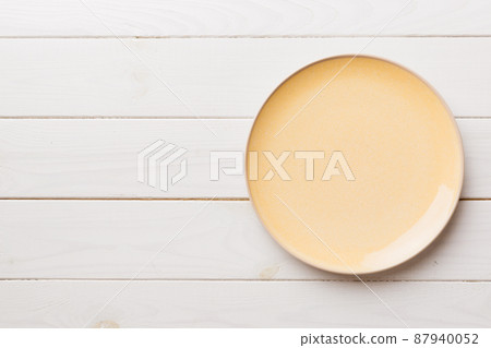 Top view of empty orange plate on wooden background. Empty space for your design 87940052