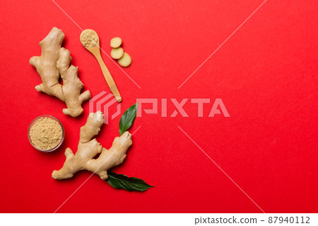Finely dry Ginger powder in bowl with green leaves isolated on colored background. top view flat lay 87940112