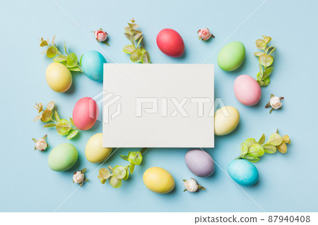 round frame multicolored Easter eggs with white blank paper on a brown background, close-up, space for text, blank for design, selective focus, tinted image 87940408