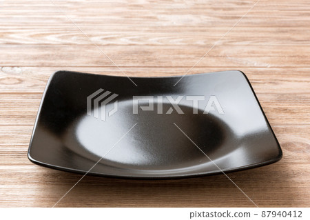 Perspective view of empty square plate on wooden background. Empty space for your design 87940412