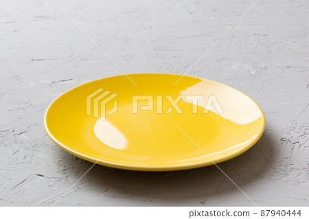 Perspective view of empty yellow plate on cement background. Empty space for your design Perspective view of empty yellow plate on cement background. Empty space for your design 87940444