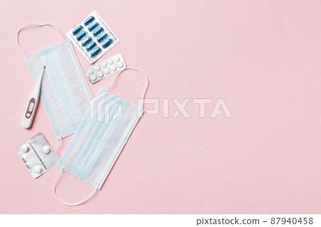 Protective face masks or surgical masks, medicine pills and thermometer on table background. Coronavirus disease. Corona virus concept. Space for text Protective face masks or surgical masks, medicine pills and thermometer on table background. Coronavirus disease. Corona virus concept. Space for text 87940458