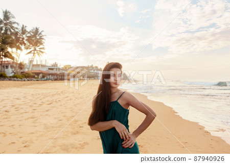 Portrait of beautiful young woman in dress on the beach. Pretty girl on tropical beach. Freedom concept, holiday, beach, sky background. 87940926