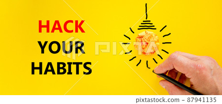 Hack your habits symbol. Businessman writing words 'Hack your habits', isolated on beautiful yellow background. Light bulb icon. Business, psychology and hack your habits concept. Copy space. Hack your habits symbol. Businessman writing words 'Hack your habits', isolated on beautiful yellow background. Light bulb icon. Business, psychology and hack your habits concept. Copy space. 87941135