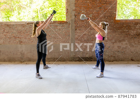 Young adult fitness women doing swing exercise with a kettlebell as a part of a fitness workout 87941783