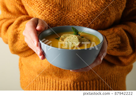 Woman holds bowl of pumpkin soup, close up 87942222