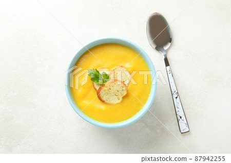 Plate of pumpkin soup and spoon on white textured table Plate of pumpkin soup and spoon on white textured table 87942255
