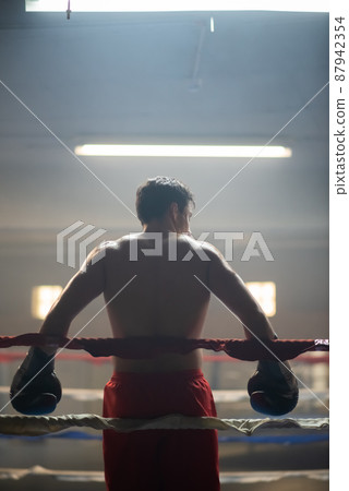 Tired athletic sportsman in boxing gloves Tired athletic sportsman in boxing gloves 87942354