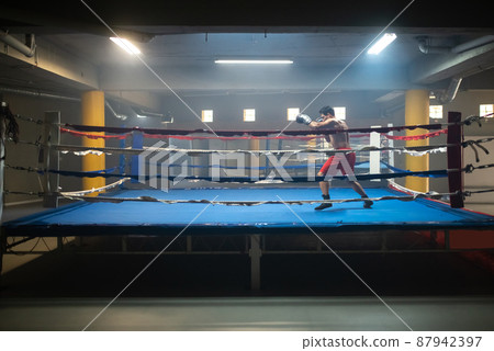 Dedicated man practicing punching technique in ring 87942397