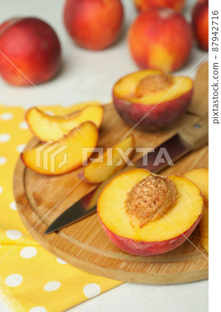 Board with peach fruits, knife and kitchen towel on white textured table 87942716