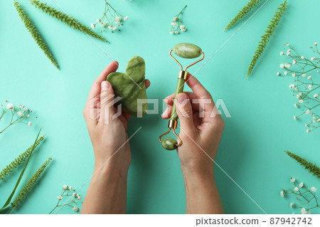 Skin care concept with face roller and gua sha on mint background Skin care concept with face roller and gua sha on mint background 87942742