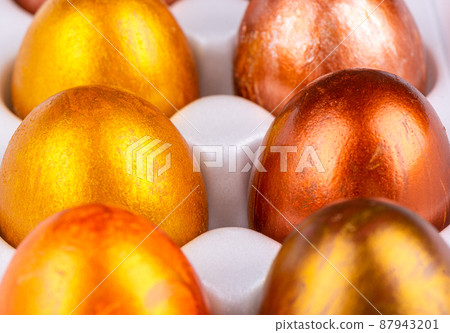 Close-up of Easter painted eggs in gold and bronze in a white package. Close-up of Easter painted eggs in gold and bronze in a white package. 87943201