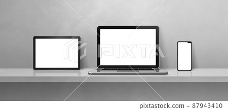 Laptop, mobile phone and digital tablet pc on grey wall shelf. Banner background Laptop, mobile phone and digital tablet pc on grey wall shelf. Banner background 87943410