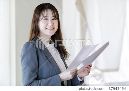 A woman holding documents and smiling A woman holding documents and smiling 87943464