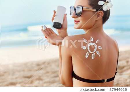 Skin and Body Care. Woman Applying Sun Cream on Tanned Shoulder In Form Of The Sun. Sun Protection.Sun Cream. Girl Using Sunscreen to Skin. Female Holding Suntan Lotion and Sunblock. Skin and Body Care. Woman Applying Sun Cream on Tanned Shoulder In Form Of The Sun. Sun Protection.Sun Cream. Girl Using Sunscreen to Skin. Female Holding Suntan Lotion and Sunblock. 87944016