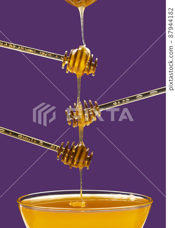 fresh honey drips from a spoon into a plate. organic vitamin health food 87944182