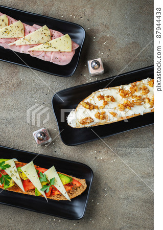 Traditional Spanish breakfast. Tostada with different toppings on a dark background. Top view with copy space Traditional Spanish breakfast. Tostada with different toppings on a dark background. Top view with copy space 87944438