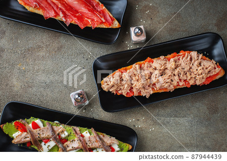 Traditional Spanish breakfast. Tostada with different toppings on a dark background. Top view with copy space Traditional Spanish breakfast. Tostada with different toppings on a dark background. Top view with copy space 87944439