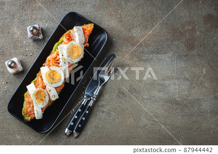 Traditional Spanish breakfast. Tostada with different toppings on a dark background. Top view with copy space Traditional Spanish breakfast. Tostada with different toppings on a dark background. Top view with copy space 87944442