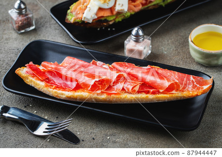 Traditional Spanish breakfast. Tostada with different toppings on a dark background 87944447