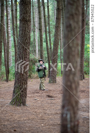 Cute boy with camera in forest Cute boy with camera in forest 87945022