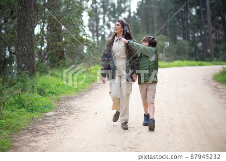 Content mother and son walking in forest Content mother and son walking in forest 87945232