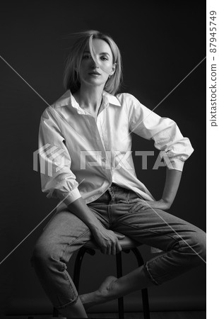 Beautiful blonde woman in a white shirt posing in the studio on a black background. Black and white photo. Model Tests 87945749