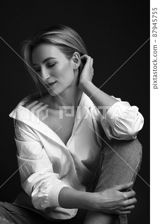 Beautiful blonde woman in a white shirt posing in the studio on a black background. Black and white photo. Model Tests 87945755