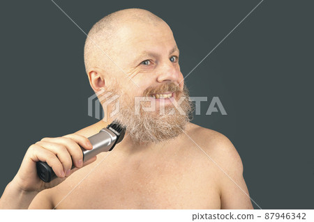 Bearded man with trimmer to adjust beard in hand. grooming and fashionable style barbershop. Bearded man with trimmer to adjust beard in hand. grooming and fashionable style barbershop. 87946342