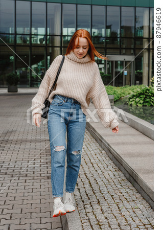 Portrait of successful happy woman on her way to work on street. Outdoor portrait of young beautiful natural redhead girl, very long hair, posing in street of city. Fashion girl with long red hair. Portrait of successful happy woman on her way to work on street. Outdoor portrait of young beautiful natural redhead girl, very long hair, posing in street of city. Fashion girl with long red hair. 87946619
