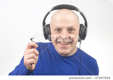 bald man with headphones on his head and an open plug in his hand. Search for a sound source bald man with headphones on his head and an open plug in his hand. Search for a sound source 87947049