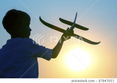 silhouette of a boy lets a model plane fly into the sky silhouette of a boy lets a model plane fly into the sky 87947051