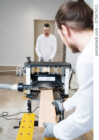 carpenters working with wood on the planing machine carpenters working with wood on the planing machine 87947411